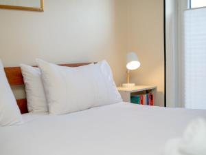 a bed with white pillows and a lamp on a table at Modern 2-Bdr Flat in Edinburgh - Pass the Keys in Edinburgh