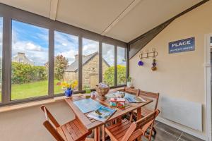 a dining room with a table and chairs and windows at Ty Line - Plage à 300 m 1 500 m² de jardin in Lampaul-Plouarzel