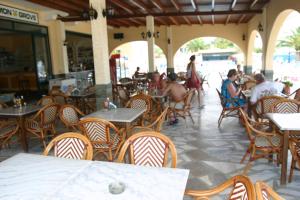 a restaurant with people sitting at tables and chairs at Lemon Grove Hotels And Studios in Kavos