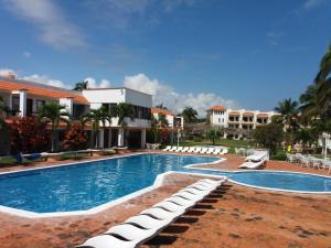 Una piscina con tumbonas junto a un complejo turístico. en Hotel Torre Molino, en Monte Gordo