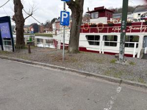 a boat parked next to a street with a parking sign at Gîte Le Sambre in Thuin