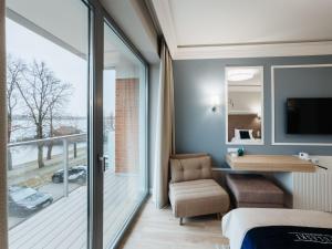 a bedroom with a balcony with a bed and a chair at Hotel Pulaski Residence in Ełk