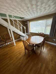 a dining room with a table and chairs and a staircase at Springfield oaks cottage in Newport
