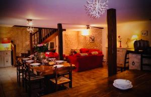 a living room with a table and a red couch at Grange authentique en Quercy in Pinsac