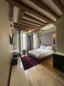 a bedroom with a large white bed and a tv at Habitat Parisien - Marais Sicile in Paris