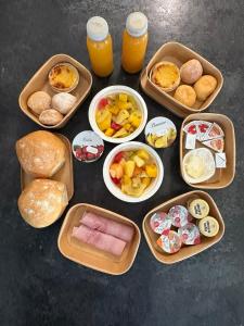 a table topped with trays of food and cups of orange juice at Gîte Le Sambre in Thuin