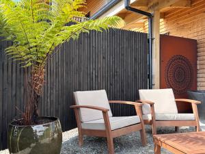 two chairs and a table and a potted plant at Pahautane Ridge - Elevated Sea Views Outdoor Stone Bath in Punakaiki +20 photos