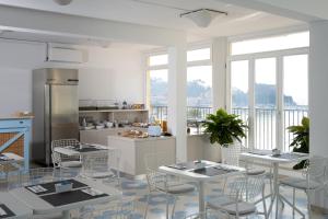 a kitchen with white tables and chairs and windows at Hotel Venere Azzurra in Lerici