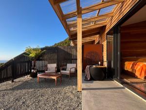 a house with a bedroom and a bed on a patio at Pahautane Ridge - Elevated Sea Views Outdoor Stone Bath in Punakaiki