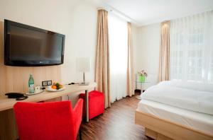 a hotel room with a bed and a desk with a television at Hotel Jägerhaus in Esslingen in Esslingen
