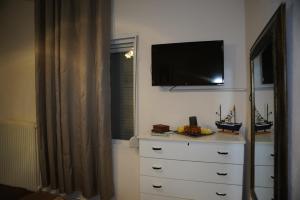 a bedroom with a dresser with a television on the wall at Trikala Apartments in Tríkala