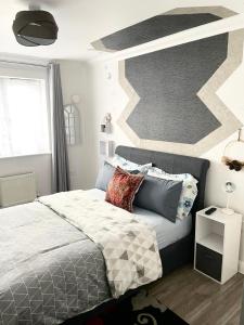 a bedroom with a bed and a geometric wall at The Grand Forsyth Apartment - Two bedroom in Dagenham