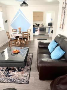 a living room with a leather couch and a table at The Grand Forsyth Apartment - Two bedroom in Dagenham