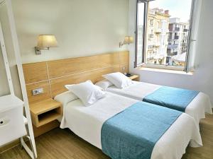 a hotel room with two beds and a window at Musika Plaza in Zarautz