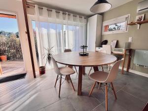 a dining room with a wooden table and chairs at Le Doux Refuge in Gujan-Mestras