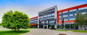 a large building with a tree in front of it at Novina Hotel Herzogenaurach Herzo-Base in Herzogenaurach