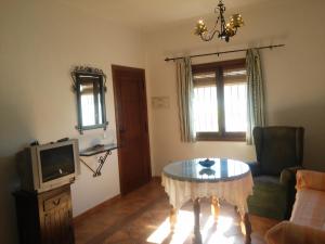 un salon avec une table et une télévision dans l'établissement Apartamentos Rurales Jardines del Visir, à Genalguacil