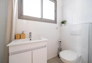 a white bathroom with a toilet and a sink at Urban Nest Yaavetz Tlv in Tel Aviv +31 photos