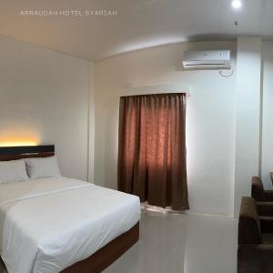 a bedroom with a white bed and a window at Arraudah Hotel Syari'ah in Paringin