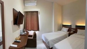 a hotel room with two beds and a television at Arraudah Hotel Syari'ah in Paringin