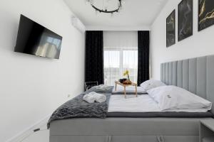 a bedroom with a bed with a tv on the wall at Luxury Apartment 23 basen i sauna D&D Apartments in Dziwnów +31 photos