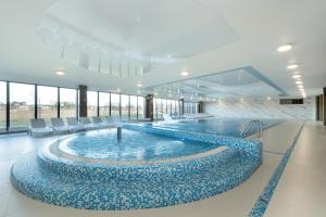 a large pool with blue water in a building at Luxury Apartment 23 basen i sauna D&D Apartments in Dziwnów