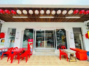 a restaurant with red tables and chairs in front of a store at Lamoon Kim Yong in Hat Yai