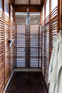 Habitación con ducha a ras de suelo y ventanas de madera. en Jicaro Island Lodge Member of the Cayuga Collection, en Isletas de Granada