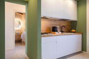 a kitchen with white cabinets and a green wall at Le Terrazze dei Candelai "boutique apartments" in Palermo