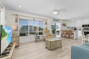 a living room with a couch and a table and a kitchen at 920 Bay Breeze Bungalow- Stunning Bay View Home with Heated Pool! home in Fort Myers Beach +22 photos