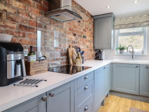 a kitchen with blue cabinets and a brick wall at Glynside in Conwy
