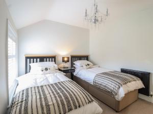 two beds in a bedroom with a chandelier at Glynside in Conwy
