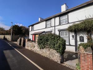 a white house with a stone wall next to a street at Glynside in Conwy