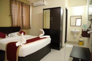 a bedroom with a bed with towel animals on it at Kalyan Residency By Azalea in Madurai