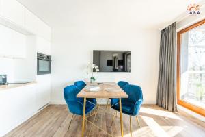a dining room with a table and blue chairs at LABA Kołobrzeg Royal Tulip Sand apartament prywatny, Basen w CENIE, Schwimmbad im PREIS in Kołobrzeg