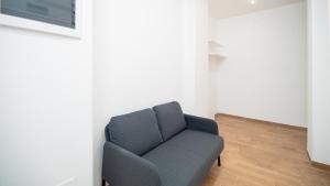 a blue couch in a room with a white wall at Lovely Rooms by Rentbeat in Civitavecchia