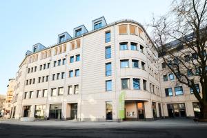 a large white building on a city street at ADAPT APARTMENT HOTEL Siegen in Siegen
