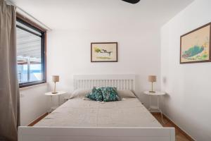 a white bedroom with a large bed with two tables at Sapore di Sale by DomuSicily in Palermo