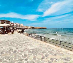 a walkway next to the beach with the ocean at Chania Vintage Escape - sea view Gem by old port in Chania Town