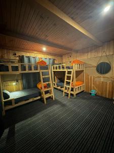 a room with three bunk beds in a cabin at Kath Kuni Cafe & Stay Shangarh in Shangarh