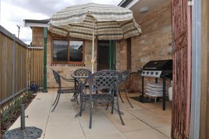 
a patio area with a table, chairs and umbrella at Apartments on Fiedler in Tanunda
