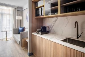 a kitchen with a sink and a couch in a room at Brussels Marriott Hotel Grand Place in Brussels