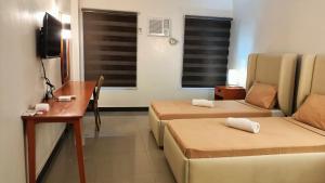 a hotel room with two beds and a couch at Grand Emilia Hotel in Cebu City +5 photos