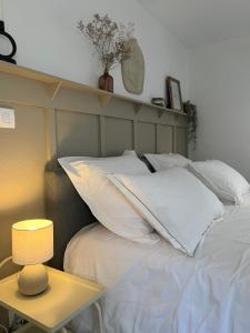 a bed with white pillows and a table with a lamp at Appartement T1 Côté jardin à Thionville in Thionville +10 photos