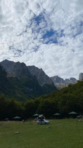 a car parked in a field with mountains in the background at lodi campers rental in Theth