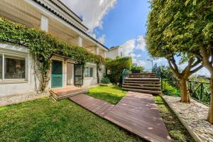een tuin met een houten looppad naast een huis bij Mbird Estoril Riviera Flat 2 in Estoril