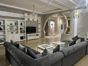 a living room with a large couch and a tv at Splendide Villa 5 chambres de luxe PRIVATISEE avec Cuisinière - Piscine chauffée - Jacuzzi & Hammam in Had Abdallah Rhiat