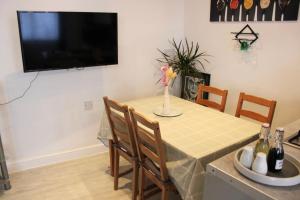a dining room table and chairs with a television on the wall at Bowery Apartment - 2 Bedrooms 1st floor in Dagenham