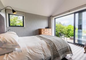 a bedroom with a bed and a large window at Nant y Rhedyn Newport in Newport Pembrokeshire