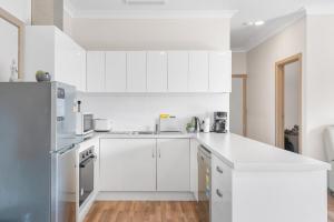 cocina blanca con armarios blancos y nevera en Modern retreat- private entrance - free parking, en Kingston